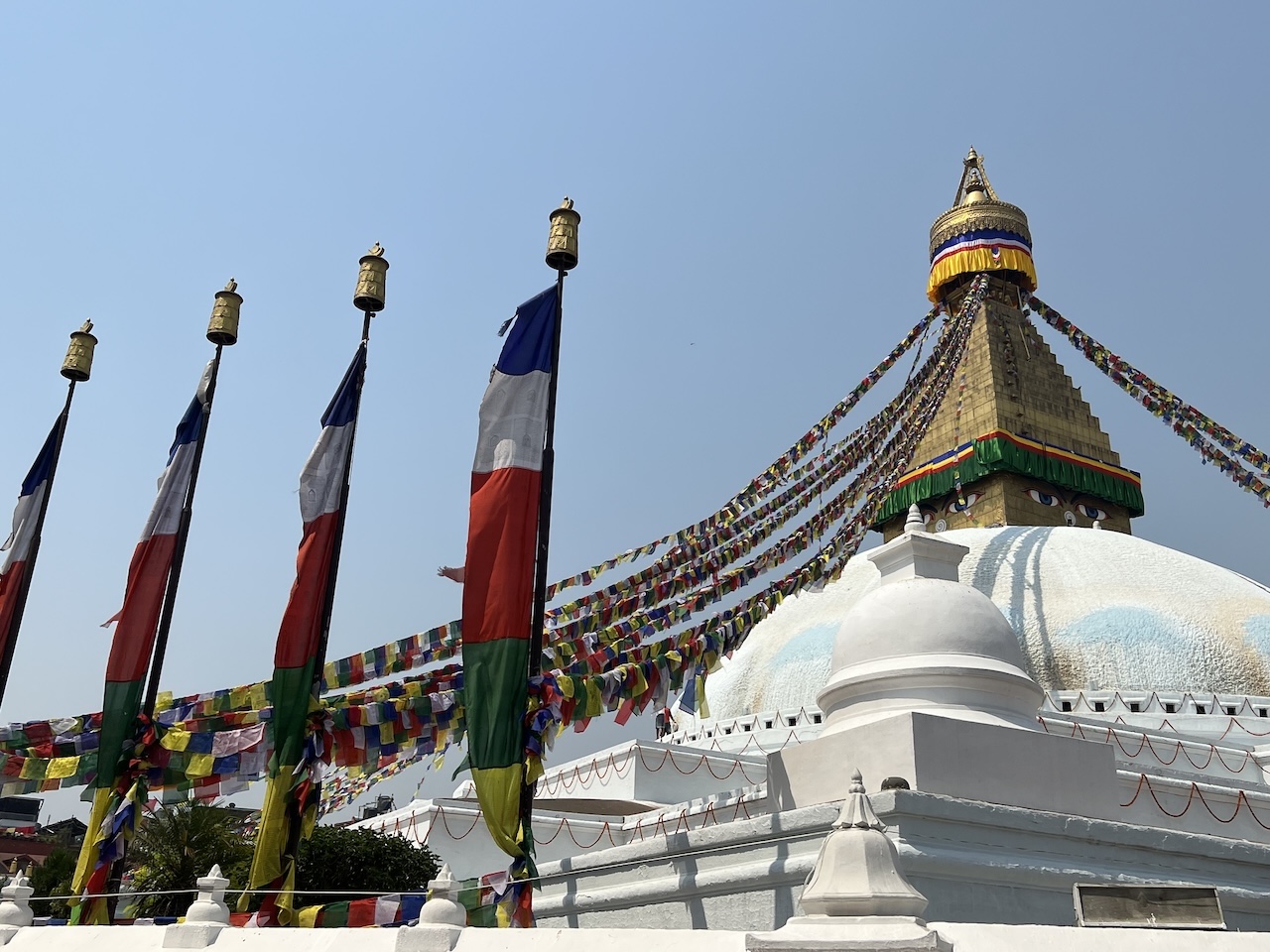 stupa Boudhanath Stupa di Boudhanath con occhi del Buddha, bandiere di preghiera e ruote dorate sotto il cielo limpido di Kathmandu