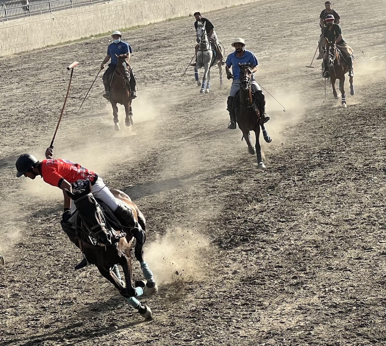 Partita polo in Pakistan Scena dinamica di una partita di polo; cavalieri con mazze su cavalli galoppano sollevando polvere sull'arena