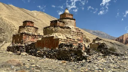 Antichi chorten in pietra e argilla, con strati di mattoni rossi, in un paesaggio montano arido sotto cielo azzurro