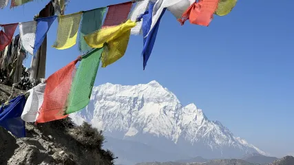 Bandiere di preghiera colorate al vento con vista sulle cime innevate del Dhaulagiri e cielo limpido