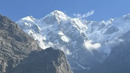 Vista ravvicinata di una maestosa montagna, con la cima completamente innevata e rocce scure in primo piano
