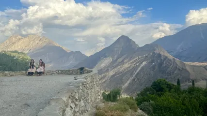 Veduta panoramica di Karimabad nella Valle di Hunza: due donne sedute su un muro con maestose montagne sullo sfondo